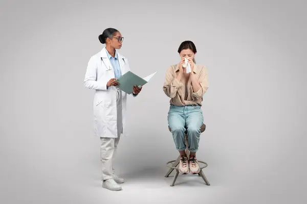 Serious black woman doctor and lady patient cry in clinic office, isolated on gray background studio. Health care problems, diseases, bad news, diagnosis and treatment, help, support