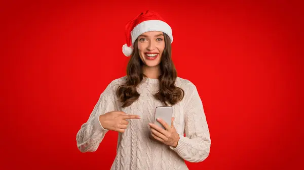 Mujer Sonriente Sombrero Santa Señalando Teléfono Celular Sonriendo Cámara Sobre — Foto de Stock