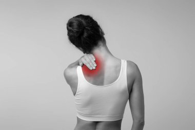 Boyun ağrısı, kas stresi ve gerginlik konsepti. Stresli esmer kadın kırmızı boyun masajı, arka görüş, siyah beyaz fotoğraf, stüdyo arka plan, fotokopi alanı