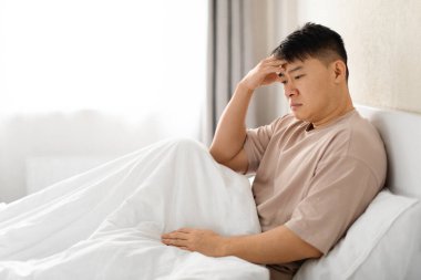 Düşünceli, orta yaşlı, düşünceli, pijama giyen, evde tek başına oturan kafası dokunan, akşamdan kalma ya da endişeli, fotokopi odası, yan görüş. Permakriz, orta yaş krizi