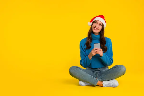 Cheerful Lady Santa Hat Texting Cellphone Sitting Cross Legged Yellow — Stock Photo, Image