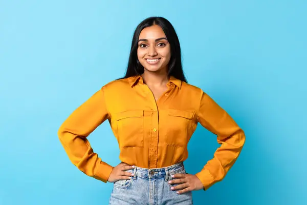 彼女の20代の陽気なインド人女性は カメラに笑顔で青い背景に対して手を握って自信を持ってポーズします 現代の広告やバナーのための肖像画 — ストック写真