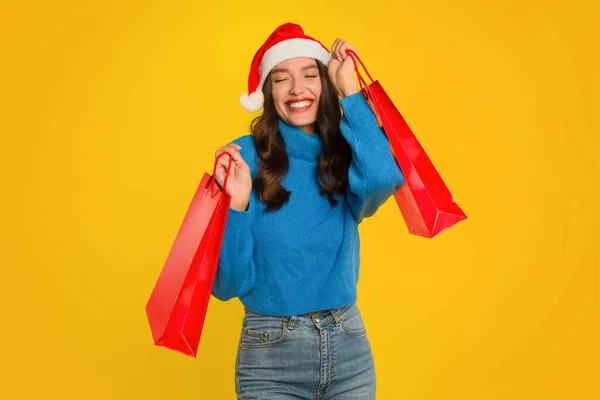 Happy Woman Blue Sweater Santa Hat Holding Red Shopping Bags — Stock Photo, Image