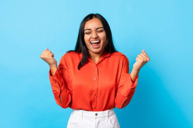 Evet, ben yaptım. Neşeli Hintli Bayan Titreyen Yumruklar Gözleri Kapalı ve sevinçle bağırıyor, Mavi Arkaplan 'a karşı büyük zafer ve başarıyı kutluyor, Stüdyo Çekimi. Kazanan Konsept