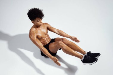 Yarı Bot Yoga Poz Veren Kaslı Adam Beyaz Stüdyoda Oturuyor, Yukarıdan Görüntü, Sportmen Gölgeleriyle Arka plan. Spor yaparken spor yapan adam üstsüz poz veriyor.