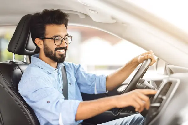 Road Playlist. Side View Profile Portrait Of Happy Indian Man Driving Car And Listening To Music On Auto Audio System, Checking Automobile Options During Test Drive Pushing Button On Turning On Radio