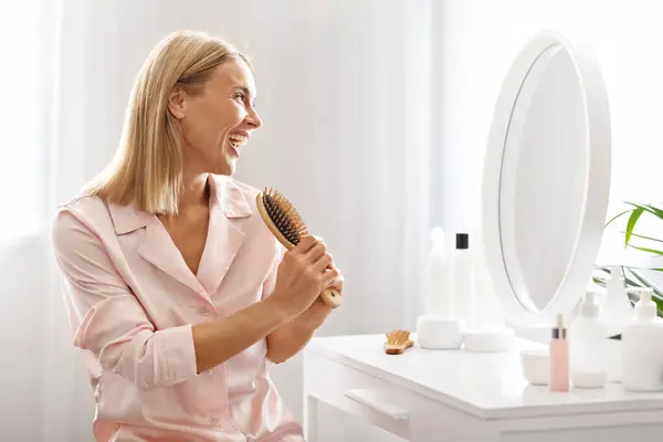 Cheerful Middle Aged Lady Singing With Hairbrush While Sitting At Dressing Table, Happy Beautiful Mature Woman Having Fun While Making Her Hair At Home, Enjoying Beauty Routine, Copy Space