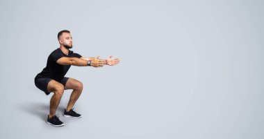 Spor giysileri içinde sakallı, sakin, yakışıklı, Avrupalı bir adam. Gri stüdyo arka planında, tam boy, panorama. Vücut bakımı, spor ve spor