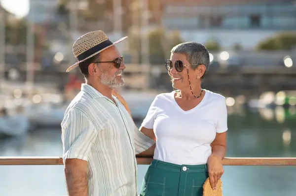 ポジティブな高齢者の配偶者は 外でドックで船の近くで夏休みの喜びを共有し 理想的な休日を経験し 海岸沿いの海洋遠征を支持し 帽子やサングラスを着用しています — ストック写真