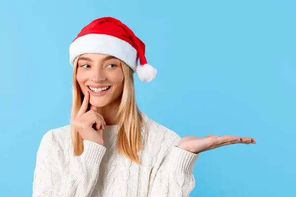 Glückliche Junge Frau Mit Weihnachtsmütze Lächelt Mit Dem Finger Auf — Stockfoto