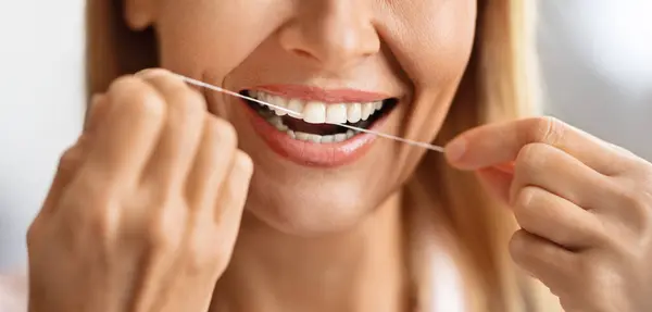 Oral Care. Closeup Shot Of Smiling Mature Female Using Dental Floss, Unrecognizable Middle Aged Woman Cleansing Perfect White Teeth, Happy Lady Making Daily Hygiene Routine At Home, Cropped Image