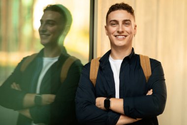 Sırt çantalı, kendine güvenen genç Avrupalı erkek öğrenci şehir ve açık havada göğsünde çapraz kollarla hayat tarzının tadını çıkarıyor. Çalışma, başarılı iş, öğrenim ve eğitim