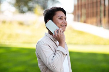 Genç Asyalı girişimci parkın önünden geçerken telefonla konuşuyor. Mutlu Milenyum Çinli işadamlarının yemek molasında fotokopi odasına bakmaları gerekiyor.