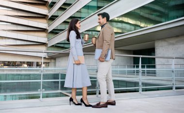 Orta yaşlı iş ortakları. Resmi kıyafetler giyen çekici erkek ve kadın. Şehir merkezinde sokakta buluşup kahve içip sohbet ediyorlar.