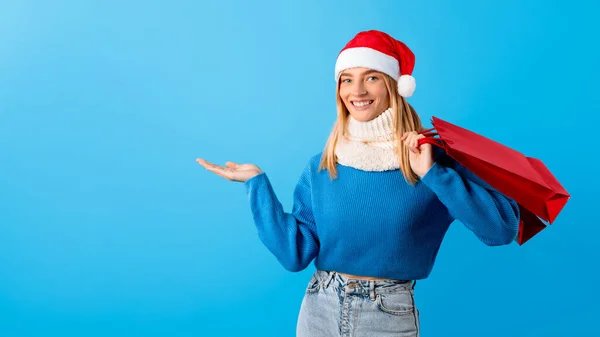 Glimlachende Jongedame Gekleed Voor Winter Santa Hoed Trots Weergeven Iets — Stockfoto