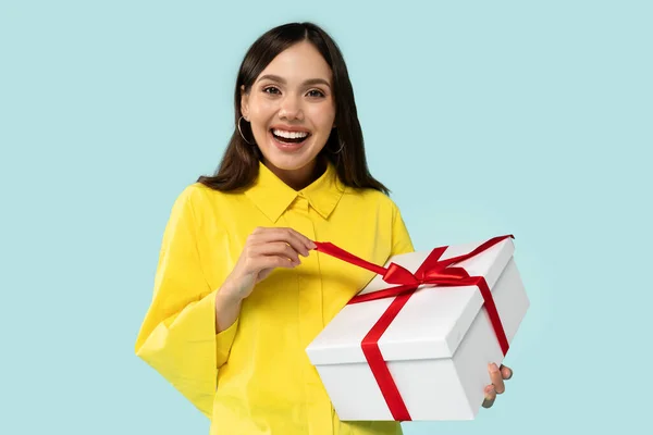 问候和庆祝 积极快乐的年轻黑发女士拿着包装礼品盒的画像 得到礼物 站在蓝色工作室的背景上 自由自在 — 图库照片