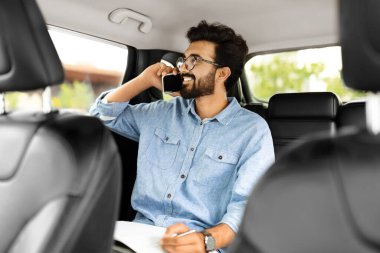 Her zaman temastayım. Gözlüklü genç Hintli menajer. Akıllı bir telefonla konuşuyor. Arabanın arka koltuğunda oturuyor, camdan bakıyor, taksiye biniyor.