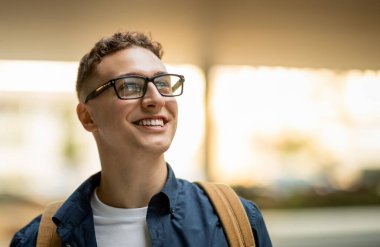 Sırt çantalı, gözlüklü, mutlu, beyaz, kıvırcık erkek öğrenci portresi. Yaşam tarzının tadını çıkar, şehirdeki fotokopi alanına bak, kapat. Eğitim ve eğitim, reklam ve teklif, satış