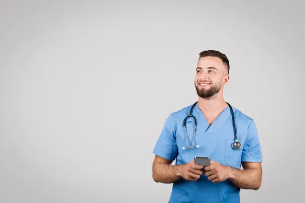 Vrolijke Jonge Europese Man Blauw Dokters Uniform Houdt Mobiele Telefoon — Stockfoto