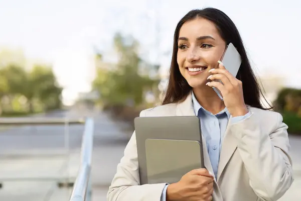 Cheerful pretty confident young woman in suit with tablet enjoy work,call by smartphone in city outdoors, look at free space. Business, startup, study and lifestyle with device, ad and offer
