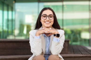 Gözlüklü, takım elbiseli, kendine güveni tam neşeli bir bayan. Şehir dışında, ofis binasının yanında iş molalarının tadını çıkarıyor. İş başarısı, yaşam tarzı, reklam ve teklif, sadece dinlenme