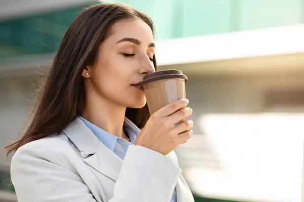 Calm pretty millennial european woman drink cup of coffee takeaway, with closed eyes, enjoy hot tea, peace in city outdoors, close up. Break from work, lifestyle, ad and offer