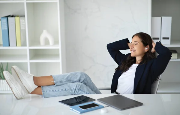 Relaxed Mature Businesswoman Listening Music Office Sitting Desk Legs Closed — Stock Photo, Image