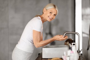 Banyo içinde yıkanan güzel, olgun bir kadın, lavabonun yanında duran çekici yaşlı bir bayan, kapalı elleriyle su toplayan, sabah temizliğini evde yapan, boşluğu kopyalayan...