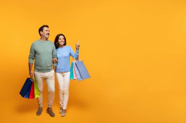 Alışverişin, serbest alanın, turuncu stüdyo arka planında izole olmanın tadını çıkaran, bir sürü çantası olan kıdemli Avrupalı karı ve koca. İlişkiler, reklam ve teklif, ilgi indirimi