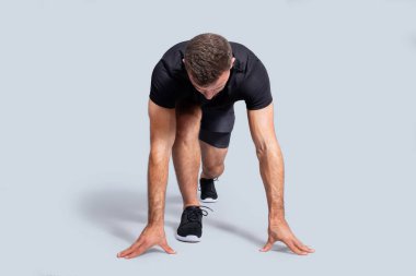 Spor giyim sektöründe güçlü beyaz erkek sporcu, çalışmaya hazır, yarışmaya hazır, gri stüdyo arka planında izole. Vücut bakımı, formda ve aktif kardiyo sporu