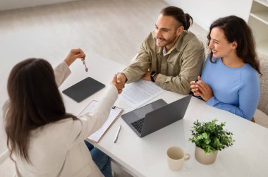 Mülk uzmanı orta yaşlı bir kadın gelişmekte olan bir çifte ev anlaşmaları ve hayat sigortası yapıyor. Emlakçı yeni evden anahtarı veriyor ve adamın elini sıkıyor.
