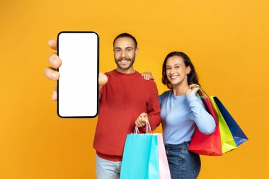 Kara Cuma anlaşması, sezon satışı, ecommerce konsepti. Neşeli milenyum çifti. İnternetten alışveriş yapan olumlu erkek ve kadın. Beyaz ekranlı akıllı telefonları gösteriyor.