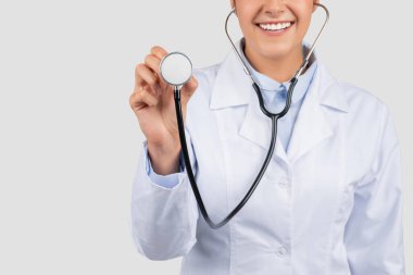 Beyaz önlüklü gülümseyen Avrupalı doktor, steteskopla nefes al, kesilmiş, gri arka planda izole edilmiş, kapat. Tıbbi muayene, sağlık hizmeti