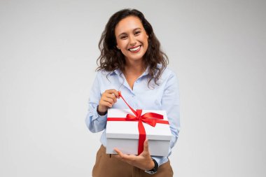 Resmi olarak giyilen bin yıllık Avrupalı bayan hediyeli açık bir kutu giyer. Gri arka plan stüdyo arka planında izole edilmiş doğum gününün tadını çıkarır. Tatil kutlaması, hediye, yıldönümünde sürpriz.