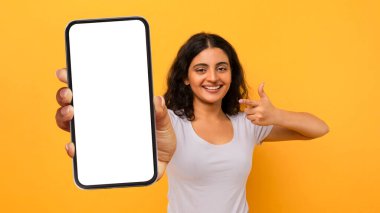 Harika bir mobil teklif. Heyecanlı bayan, elinde akıllı telefonu işaret ediyor, yeni uygulamaya duygusal tepki veriyor, Orange Studio 'nun arka planında yalnız duran mutlu Hintli kadın, Panorama