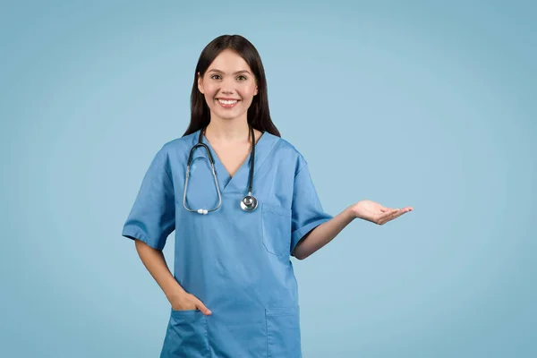 Щаслива Молода Медсестра Блакитних Скрабах Представляє Відкритою Рукою Жест Носить — стокове фото