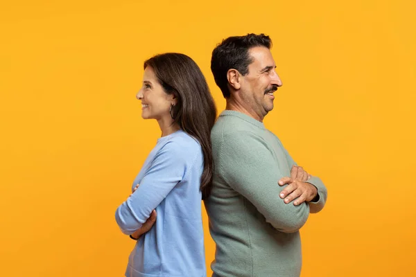 Happy confident senior caucasian family in casual, back to back with crossed arms on chest, isolated on orange studio background. Family lifestyle, relationships and team