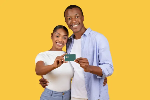 Uśmiechnięta Młoda Czarna Para Wspólnie Prezentująca Kartę Bankową Wyglądająca Radośnie — Zdjęcie stockowe