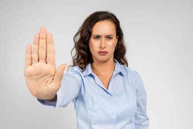 Resmi olarak giyinmiş üzgün bin yıllık Avrupalı kadın gri arka plandaki stüdyo arka planında izole bir şekilde dur işareti yapıyor. İşle ilgili sorunlar, cinsiyetçilikle mücadele, taciz