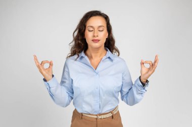Resmi olarak, bin yıllık Kafkasyalı bayan yönetici gri arka planda izole edilmiş gözlerle meditasyondan, nefes egzersizlerinden ve meditasyondan hoşlanır. İşten, eğitimden ve işten, barıştan