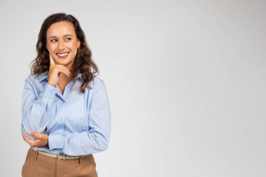 Neşeli, düşünceli, bin yıllık beyaz kadın menajer, resmi olarak giyinen öğretmen, boş alana bak, düşün, arka plandaki gri arka plan stüdyosunda izole edilmiş. Çalışma, öğrenim, kurslar ve iş fikri oluşturma