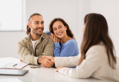 Başarılı Anlaşma Konsepti. Milenyum Çifti 'nin Yeni Bir Daire Alırken Portresi, Profesyonel Emlakçıyla Tokalaşmak. Gülümseyen Takım Elbiseli Müdür Mutlu Genç Aileye Daire Satıyor