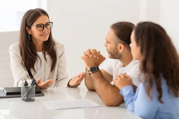 stock image Content young married partners in a session with a realtor attractive middle aged woman, examining documents in a professional setting, asking their agent questions