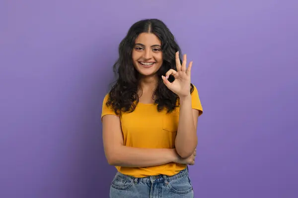 ポジティブかわいいかわいい若いヒンドゥー教の女性の学生は 紫色のスタジオの背景に隔離されたカメラで大丈夫なジェスチャーと笑顔を示し 良いまたはサービスをお勧めします — ストック写真