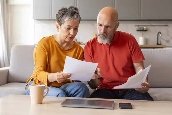 Stressed Senior Couple Checking Financial Papers And Planning Budget At Home, Upset Elderly Husband And Wife Looking At Loan Documents, Suffering Crisis While Calculating Family Spends, Closeup