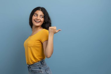 Özel bir teklif. Sırıtkan Hintli genç bir kadının portresi, arka plandaki mavi stüdyoya bakarak fotokopi alanını işaret ediyor. Boş yer gösteren heyecanlı kadın, reklam için yer
