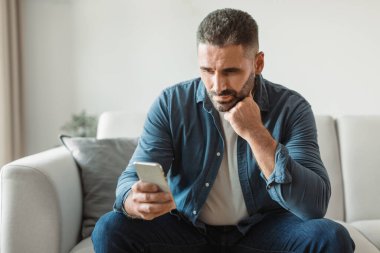 Düşünceli orta yaşlı bir adam evdeki telefonunda kıyamet tomarları taşıyor. İş adamı hayal kırıklığıyla dolup taşıyor ve modern oturma odasındaki yeni mobil uygulamayla çevrimiçi olarak sorun yaşıyor