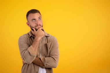 Düşünceli, sakallı, turuncu stüdyo arka planında soyutlanmış beyaz bir adam. Seçim, yaşam tarzı ve insani duygular, iş, satış, fikir oluşturma için reklam ve teklif