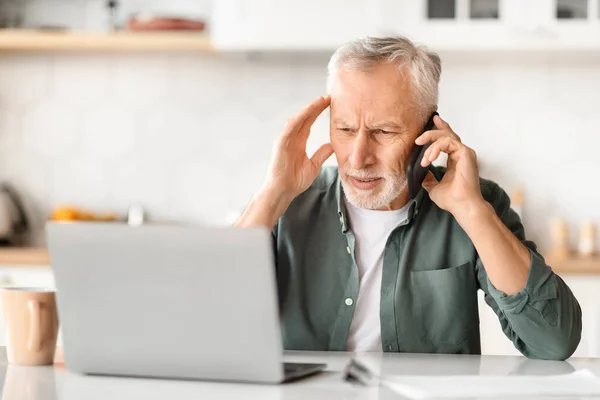Stressed Senior Man Using Phone Laptop While Sitting Desk Kitchen — Stock Photo, Image