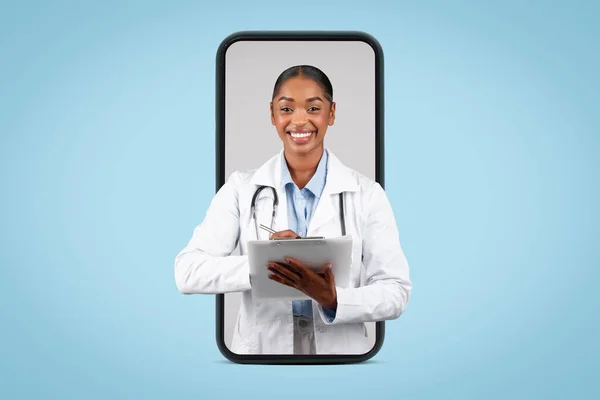Happy millennial black woman doctor write at clipboard on big smartphone screen, isolated on blue background, studio, collage. Medical consultation app remotely and blog website